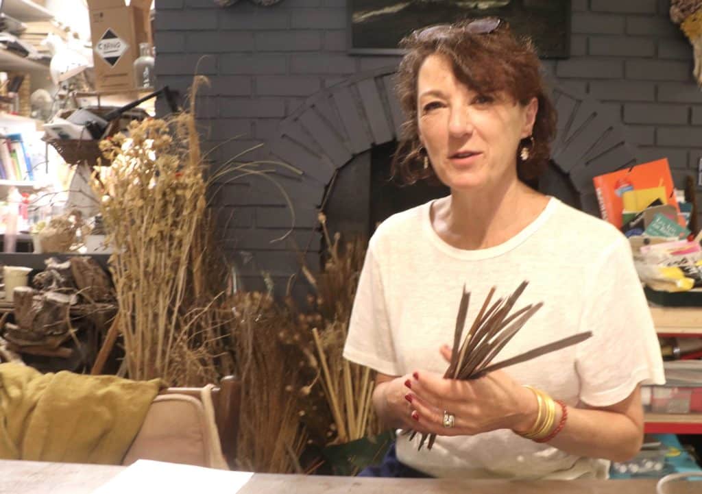 Béatrice Begon dans son atelier, montrant des gousses de catalpa