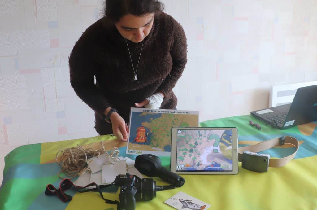 Cécile Saba, devant une table où sont déposés différents outils technologiques.