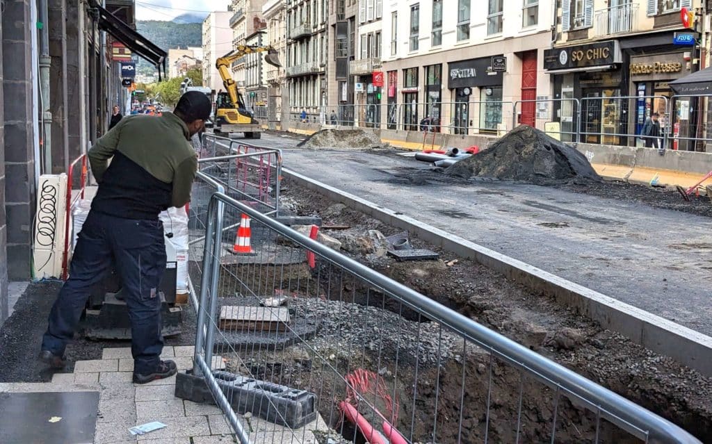 La rue Blatin en travaux, laissant peu de place à un livreur qui tente de faire avancer son chariot sur un trottoir très réduit.