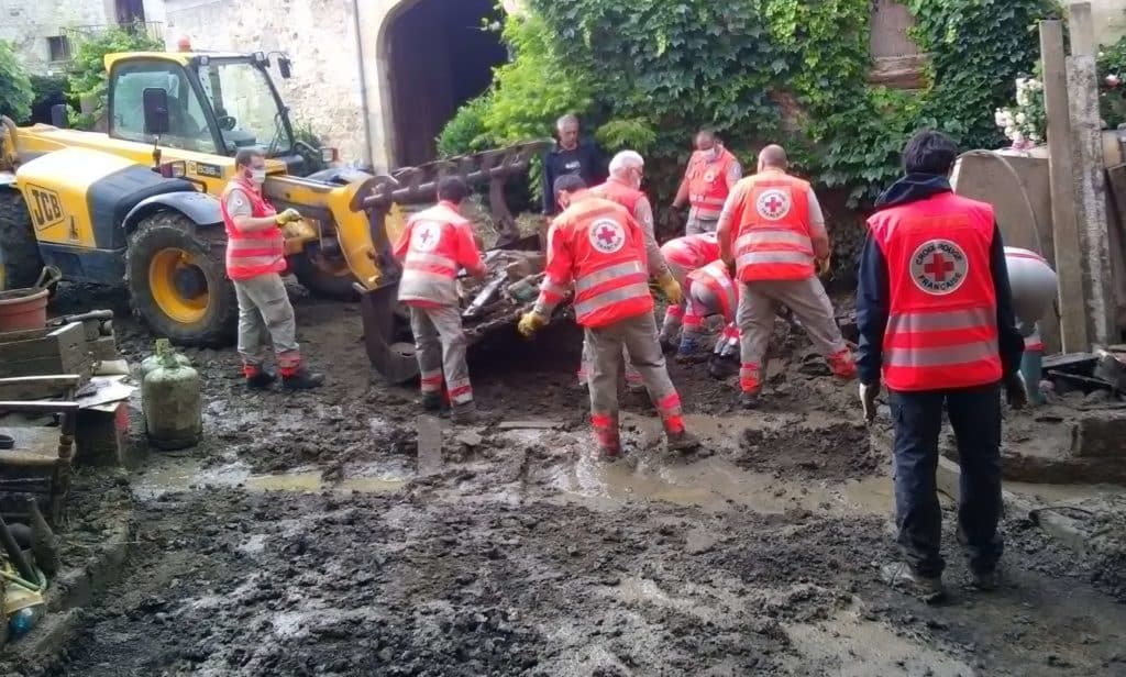 Bénévoles de la Croix-Rouge dégageant la boue dans une rue