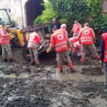 Bénévoles de la Croix-Rouge dégageant la boue dans une rue