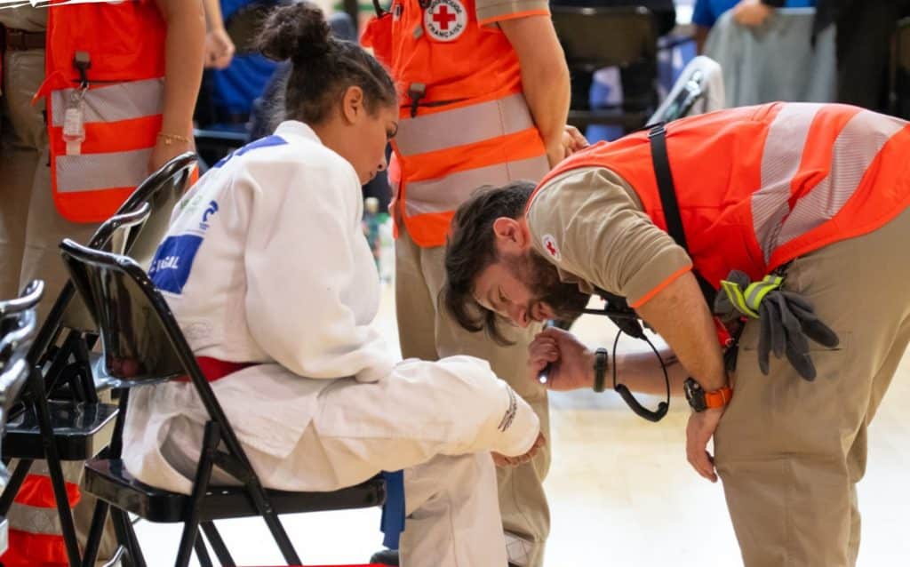 Un secourisme examine la jambe d'une jeune judokate