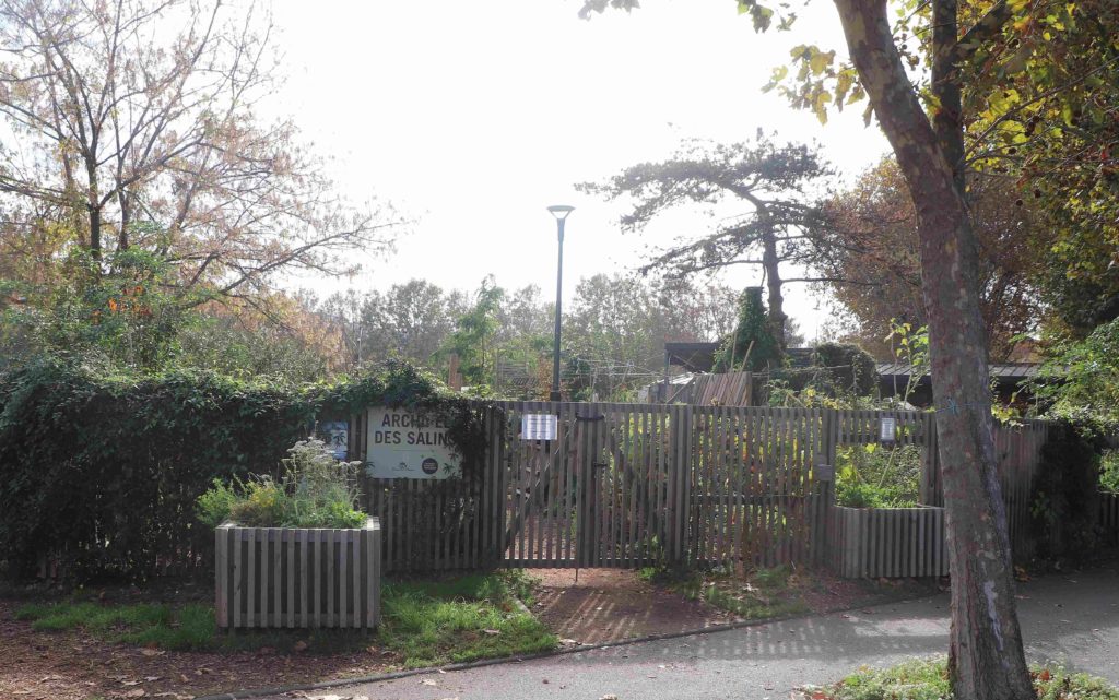 L'entrée du jardin encadré de verdure, avec la pancarte "Archipel des Salins"