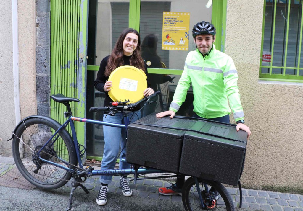 Agathe et Mika devant le local de Raboule, avec une boîte à pizza et le vélo-cargo