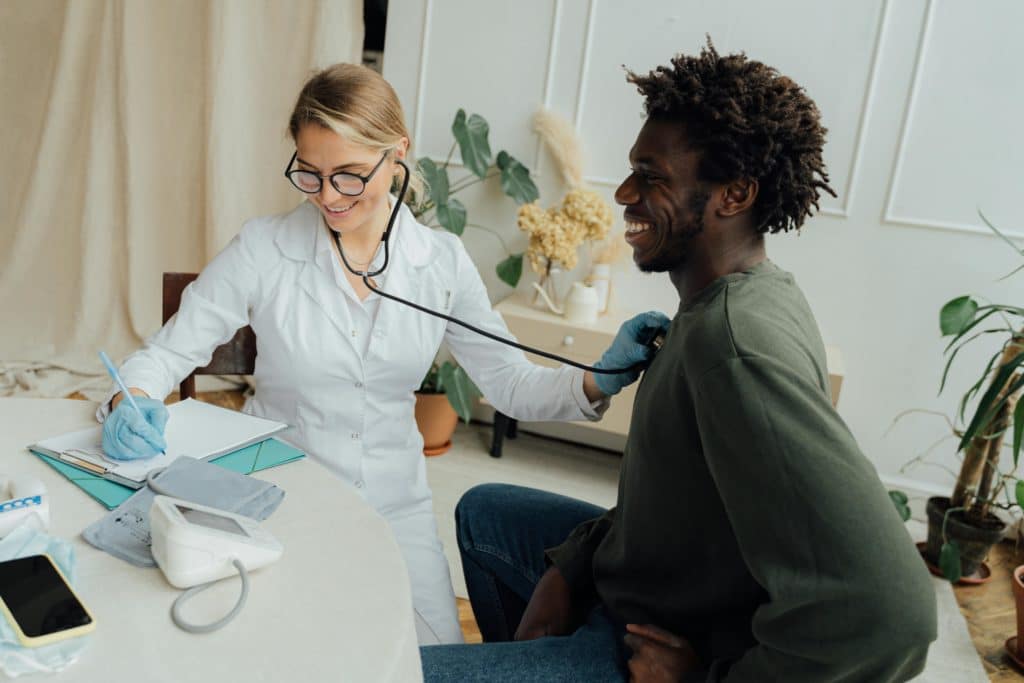 Médecin auscultant un homme jeune, dans une ambiance détendue et souriante